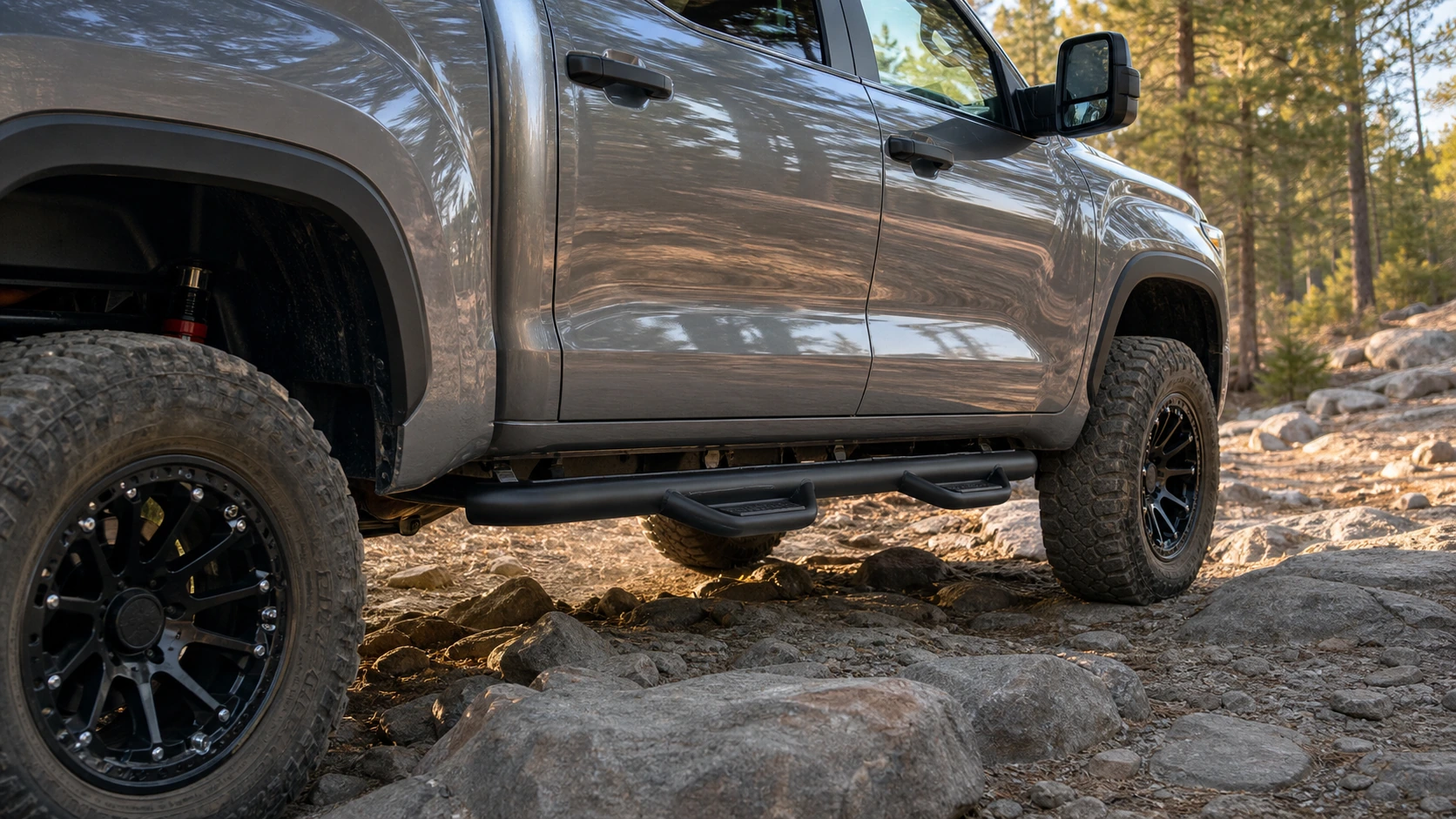 Wheel-to-wheel nerf bar clearing rocks beneath a full-size crew-cab pickup